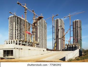 Four tall buildings under construction with cranes against a blue sky - Powered by Shutterstock