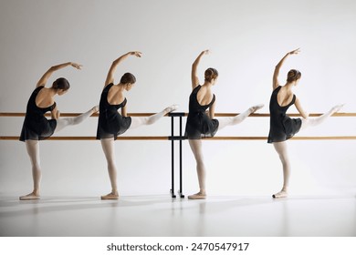 Four teen girls, ballet dancers, training with barre, standing in pose with one leg extended against grey studio background. Concept of ballet, art, dance studio, classical style, youth - Powered by Shutterstock