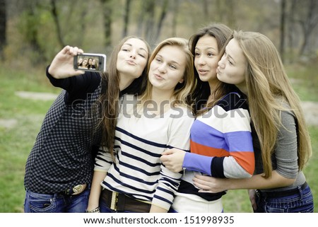 Four teen girls pretty young women taking selfshot or selfy picture of themselves happy smiling having joyful time & fun outdoors portrait
