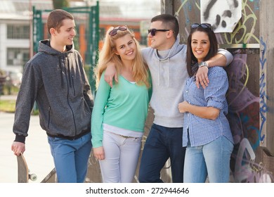 Four teenage friends having fun in a skate park
