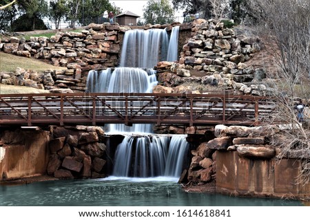 Four tier water fall surrounded by rocks with walking bridge in Wichita Falls Texas.