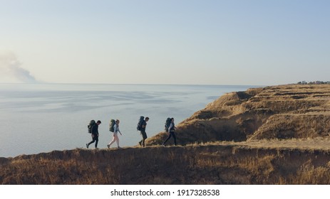 The four tourists walking on the rocky coastline - Powered by Shutterstock