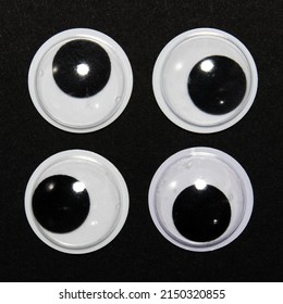 Four Toy Eyes In A Square Look In Different Directions. Isolated On Dark Background