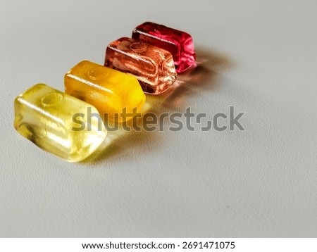 Four transparent, rectangular candies lie on a white surface.