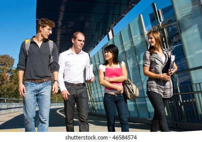 Four University Students Walking To Class Over A Modern Bridge On A Beautiful Sunny Day