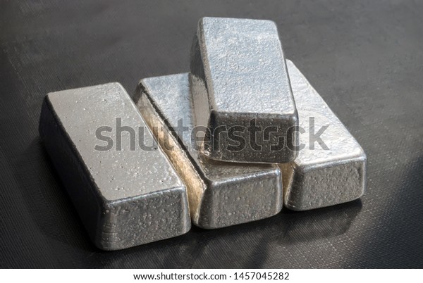 Four unmarked silver bars on a dark background.\
Selective focus. 