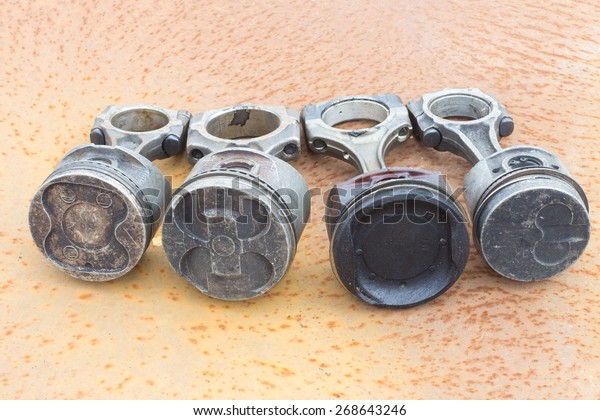Four various\
piston rods lie on rusty\
metal