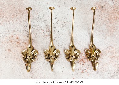 Four vintage brass Fleur de Lis wall hooks hangers on concrete background. Copy space for text.