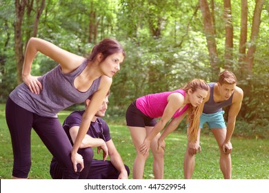 Four weary friends resting after working out in a park leaning forwards on their knees in their sportswear in a healthy lifestyle concept - Powered by Shutterstock