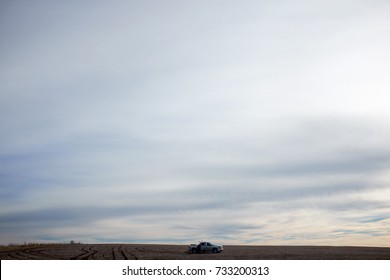 A Four Wheel Drive Car In A Vast, Barren Desert Landscape Under A Stormy, Overcast Sky.