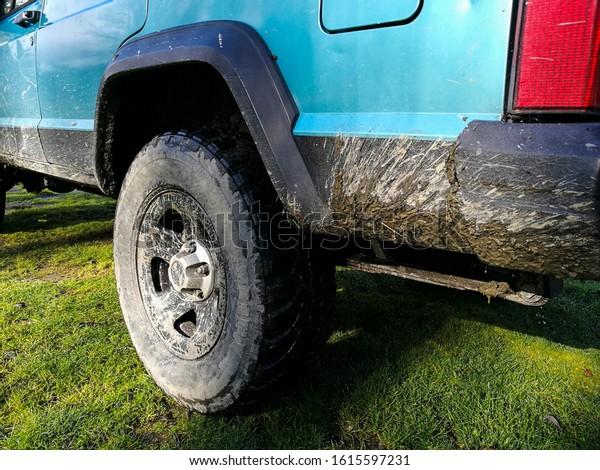A four wheel drive vehicle with mud on it\'s wheel\
and body.