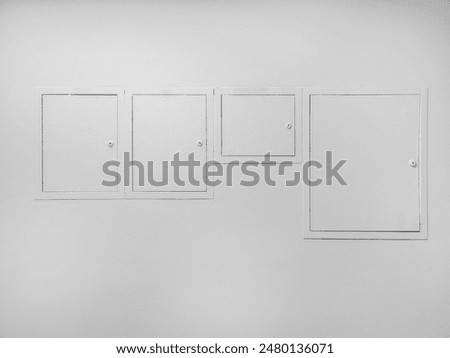 Four white electric meter boxes of different sizes on a white wall.	
