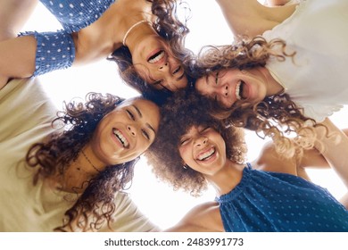 Four women with curly hair hugging each other are smiling and standing in a circle. The scene is happy and joyful - Powered by Shutterstock