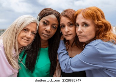 Four women embracing outdoors. Radiating love and support with genuine smiles. Showcasing unity and sisterhood across generations and ethnicities under a cloudy sky. Authentic relationships captured - Powered by Shutterstock