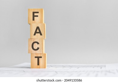four wood cubes with the word FACT on the background of white financial statements, strong business concept. gray background