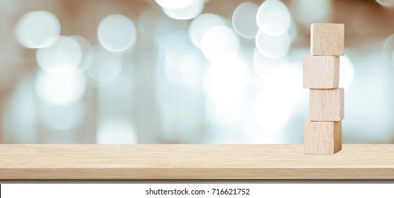 Four wooden block cubes on wood table over blur abstract bokeh light background, banner with copy space for text, poster, mockup template