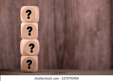 Four wooden blocks with black question marks.