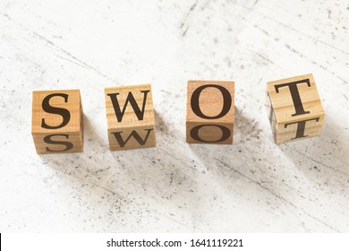 Four wooden cubes with letters SWOT (meaning Strength, Weakness, Opportunity, and Threat Analysis) on white working board. - Shutterstock ID 1641119221