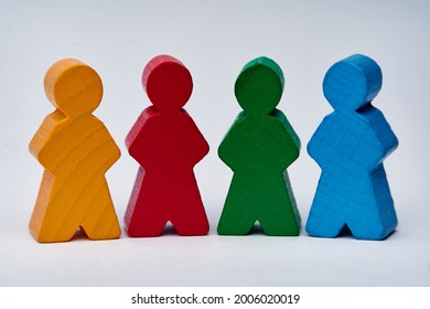 Four wooden toy guys which can symbolize a team of people of various personalities (red, yellow, green, blue). White background