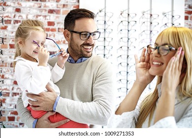Vier Jahre kleines Mädchen in der Optik Geschäft wählen Brille mit ihrem Vater. Der Ophtamologe hilft.