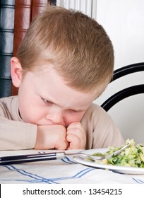 Four year old boy disliking the food on his plate