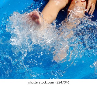 A Four Year Old Boy Kicking In A Blue Kiddie Pool.