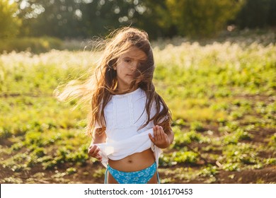 four year old tan girl with long hair, developing hair, blurred background, outdoors