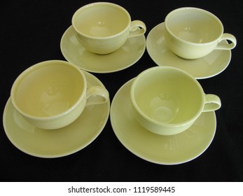 Four Yellow Mid Century Modern Ceramic Coffee Cups And Saucers On A Black Limbo Background Are A Retro Vintage Image 