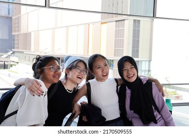 Four young attractive Asian group woman friends colleagues students talk walk discuss mingle outdoors backpack handphone outdoor notebook urban building cityscape look show point happy