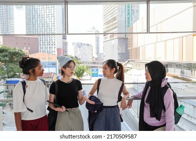 Four young attractive Asian group woman friends colleagues students talk walk discuss mingle outdoors backpack handphone outdoor notebook urban building cityscape