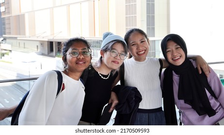 Four young attractive Asian group woman friends colleagues students talk walk discuss mingle outdoors backpack handphone outdoor notebook urban building cityscape look happy