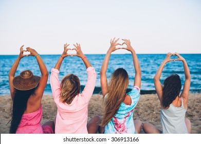 Four young beautiful girl hats sit on the beach - Powered by Shutterstock