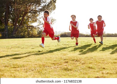 Four young boys in football strip running in a playing field