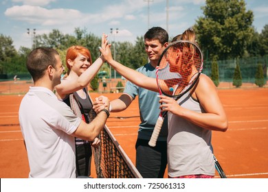 Four young friends giving a high-five after tennis training. Selective focus. - Powered by Shutterstock