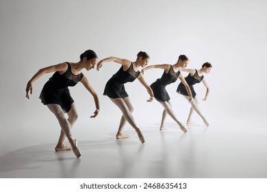 Four young girls, ballet dancers in black leotards training, showing flexibility and synchronized choreography on grey studio background. Concept of ballet art, dance studio, classical style, youth - Powered by Shutterstock