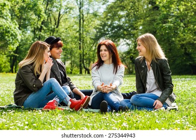 Four Young Girls Sitting In The Park And Talking.Did You Hear?!