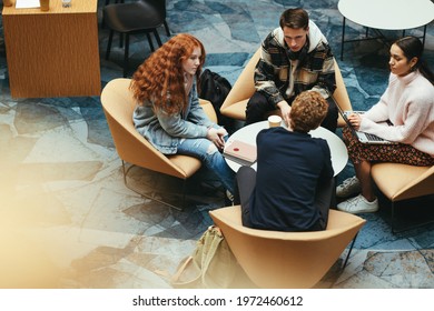 Four Young People In School Campus Doing Working On Project. Young Students Discussing Studies In Campus.