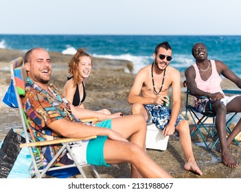 four young people sunbathing on a rocky beach