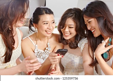 Four Young Women Looking And Discussing About Something On Cell Phone