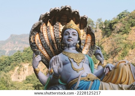Four-armed Lord Vishnu against the backdrop of mountains in Rishikesh, Uttarakhand, India.
