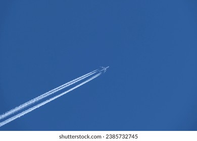 Four-engined jet aircraft in the blue sky and its contrail