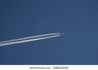Four-engined jet aircraft in the sky and its contrail at sunset.