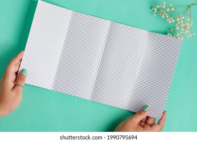 Four-fold Brochure Mockup In A Hand Above Aquamarine Background