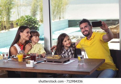 A Four-member Family Having Great Time In A Restaurant, Make Selfie Photo