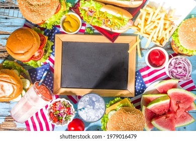 Fourth Of July, Memorial Day, USA Independence Day Concept. Patriotic, American Traditional Food. Picnic Party With Watermelon, Burgers, Hot Dogs, Drinks, Blue Wooden Outdoor Table Background