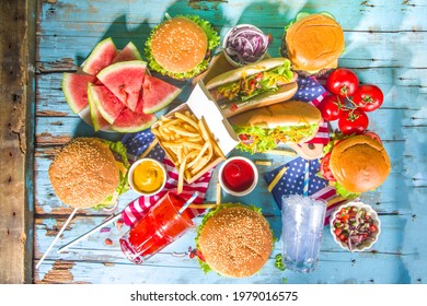 Fourth Of July, Memorial Day, USA Independence Day Concept. Patriotic, American Traditional Food. Picnic Party With Watermelon, Burgers, Hot Dogs, Drinks, Blue Wooden Outdoor Table Background