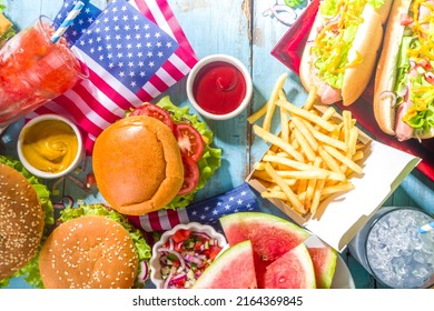 Fourth Of July, Memorial Day, USA Independence Day Concept. Patriotic, American Traditional Food. Picnic Party With Watermelon, Burgers, Hot Dogs, Drinks, Blue Wooden Outdoor Table Background