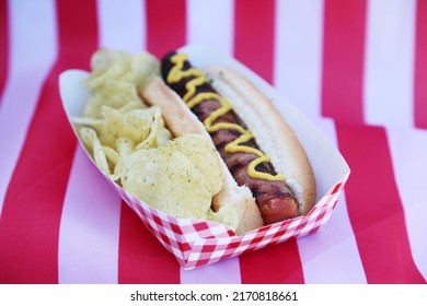 Fourth Of July Party HOT DOG. Fresh Cooked Hot Dog In A Bun. Fresh Cooked HOT Dog With Chips On An American Flag. 4th Of July BBQ Party. Party Food. Independence Day Hot Dog. Lunch. Dinner. Snack.