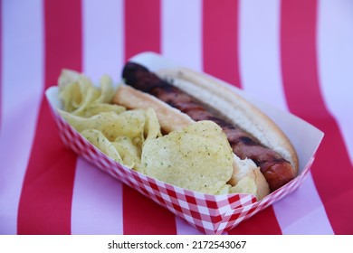 Fourth Of July Party HOT DOG. Fresh Cooked Hot Dog In A Bun. Fresh Cooked HOT Dog With Chips On An American Flag. 4th Of July BBQ Party. Party Food. Independence Day Hot Dog. Lunch. Dinner. Snack.