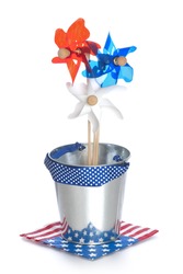 Fourth Of July Red White And Blue Pinwheels In A Bucket On A Flag Napkin Isolated On White Background.